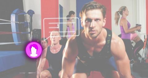 Intense male athlete squatting in group training studio with neon fitness ui overlay