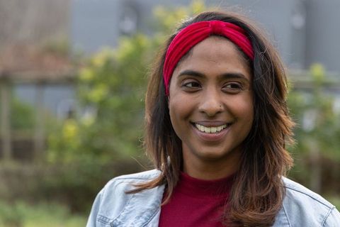 Indian woman smiling in backyard wearing red headband and denim jacket casual portrait