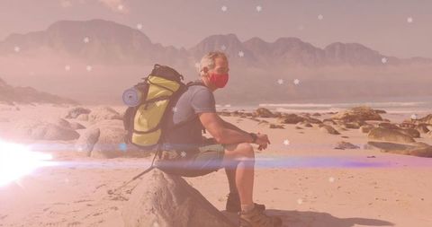 Middle-Aged Hiker With Green Backpack Relaxing On Sandy Beach