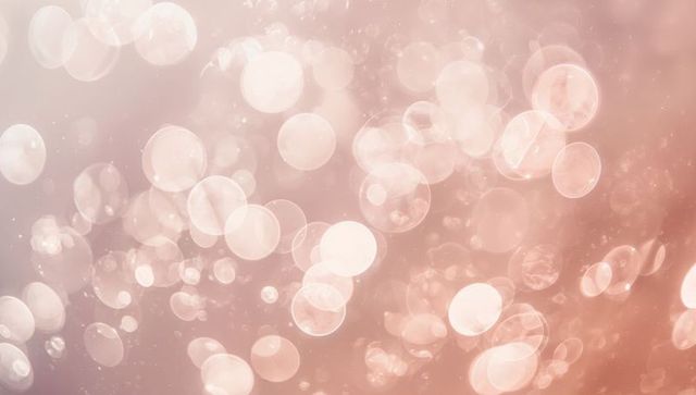Soft peach pink bokeh with glowing translucent orbs floating over dreamy gradient