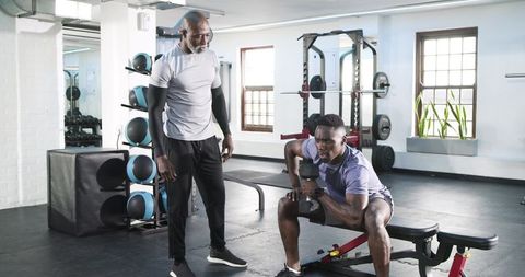 Trainer Guiding Gym Workout with Dumbbells