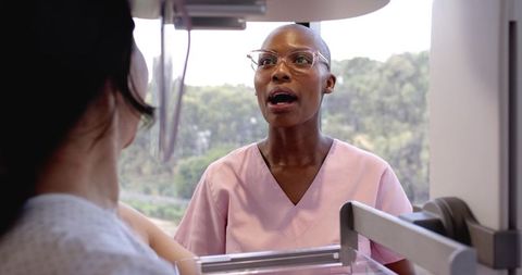 Radiology Technician Guiding Patient Through Mammogram in Sunlit Clinic Room