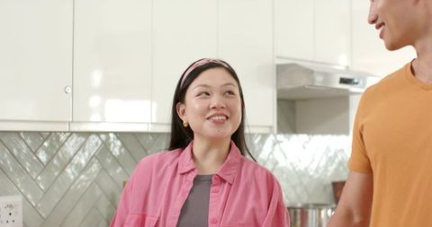 Smiling couple chatting in modern kitchen with glossy chevron backsplash and cookware