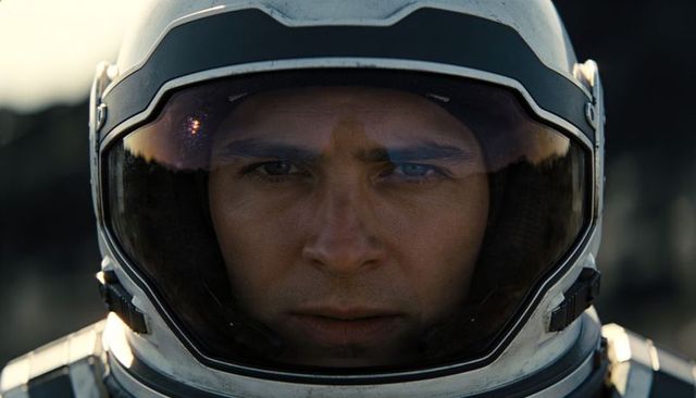 Intense astronaut closeup with reflective visor and rocky horizon cinematic portrait