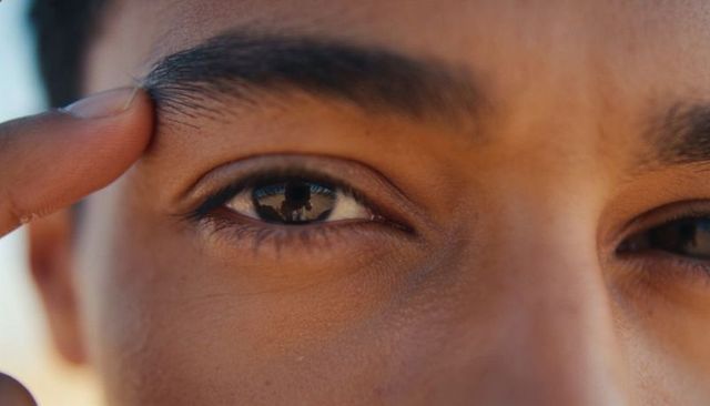 Closeup man touching eyebrow showing camera reflection in eye skin texture sunlight