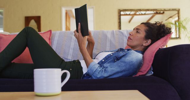 Caucasian woman reading book, lying on sofa at home - Download Free Stock Photos Pikwizard.com
