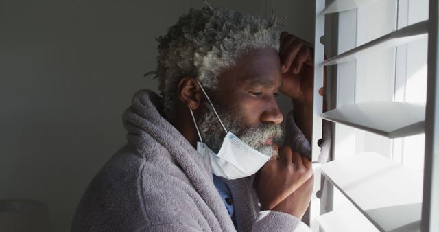 Pensive Elderly Man with Mask by Window Observing Light - Download Free Stock Images Pikwizard.com