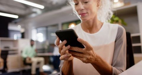 Woman Navigating Smartphone in Modern Office Environment