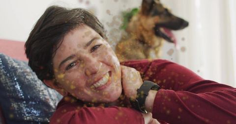 Smiling woman relaxing on sofa with german shepherd wearing smartwatch, cozy home moment