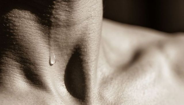 Sepia close-up of neck texture with single water droplet on clavicle, high contrast macro