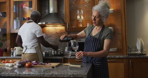 Senior Woman Pouring Wine in Cozy Kitchen