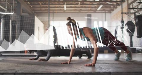 Partners doing push-ups with fitness data overlay in industrial sunlit training studio