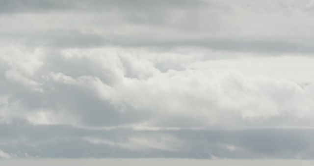 This image portrays a cloudy sky with layers of soft grey clouds, creating a subdued, moody atmosphere. It is ideal for use in weather forecasts, climate-related articles, and presentations emphasizing nature's serene, cloudy aesthetic. This image can also serve as a backdrop for motivational quotes and posters aimed at invoking a calm, reflective mood.