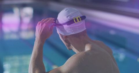 Male Swimmer Adjusting Goggles at Indoor Pool Ready for Dive