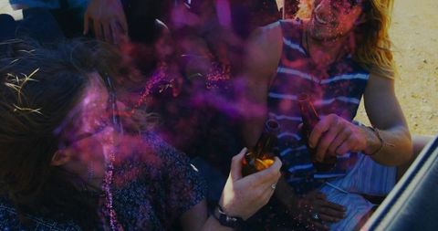 Friends enjoying beer with colorful haze in open vehicle trunk