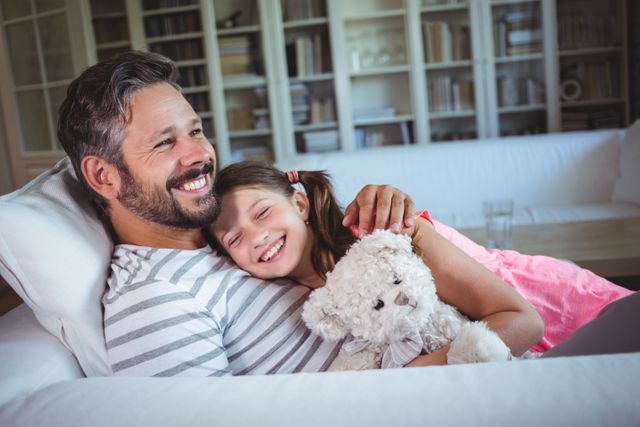 Happy father lying on sofa with daughter in living room