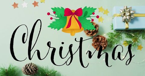Hand-lettered christmas script on mint green flatlay with holly bell, gift and pinecones