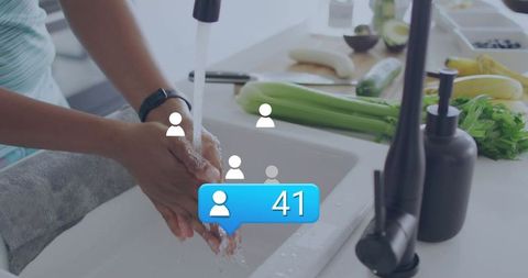Middle aged woman washing hands at kitchen sink with social notification 41 for hygiene