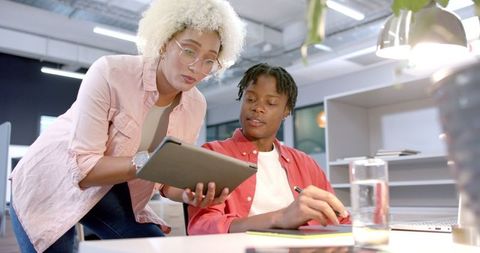 Young colleagues collaborating with tablet in modern office