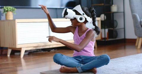 African american girl using wireless vr headset at home interacting with virtual world