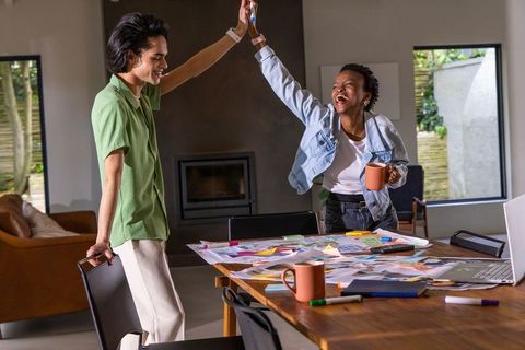 High-fiving coworkers celebrating creative breakthrough during collaborative design session