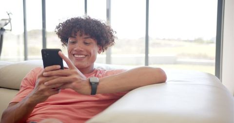 Young Man Relaxing on Couch Engaged with Smartphone - Download Free Stock Images Pikwizard.com