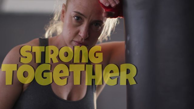 Caucasian female boxer training intensely with the motivational text 'Strong Together' superimposed. The video highlights her focus and determination, emphasizing themes of fitness, strength, and teamwork. Suitable for use in fitness campaigns, motivational posters, gym advertisements, and digital content promoting health and wellness.