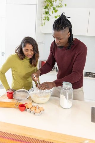 Diverse couple whisking batter together in modern kitchen creating cozy baking moment