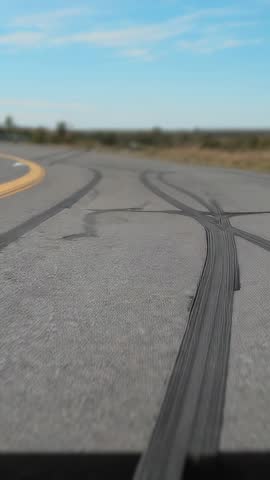 Vertical video capturing rural road with dramatic tire skid arcs and yellow centerline motion
