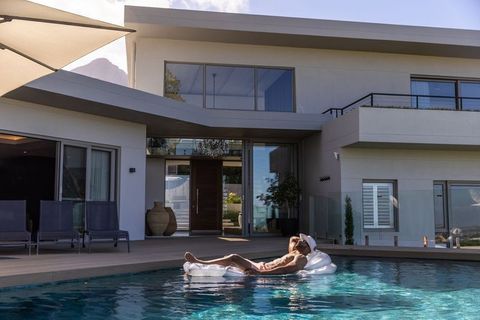 African american man lounging on clear float in sunlit pool at modern villa terrace