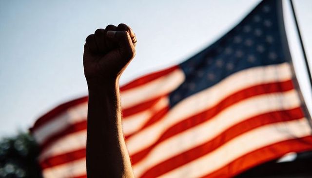 Raising clenched fist against waving american flag for protest unity and patriotism