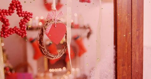 Hanging rustic heart wreath on frosted window with cozy christmas stockings and warm bokeh