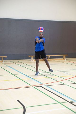 African american male performing forearm pass volleyball action in indoor gymnasium