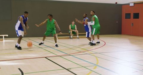 African american guard driving past defender on court freeing teammate for shot