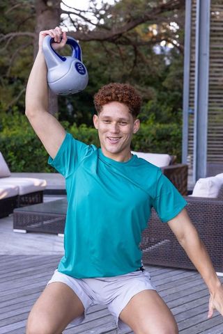 Young Man Exercising with Kettlebell on Outdoor Deck