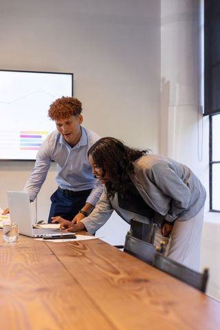Diverse team collaborating at laptop in modern meeting room for presentation and analytics