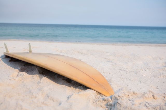 Wooden surfboard on sand at beach during sunny day
