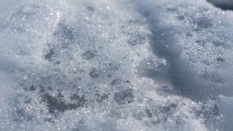 Melting Snow Turning into Water Droplets and Sparkling Ice Crystals on Sunlit Path