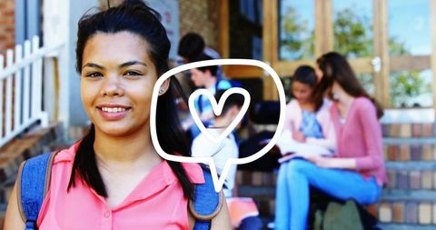 Smiling high school student standing on campus with heart chat bubble and backpacks