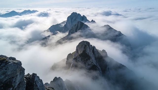 Jagged Alpine Peaks Piercing Low Clouds on Misty High Ridge with Exposed Rock Faces