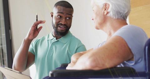 Caregiver Discussing Care Plan Using Tablet and Pen with Senior Woman in Wheelchair