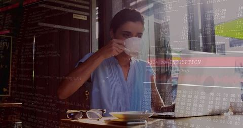 Sipping coffee while typing on laptop with encryption code overlay in urban cafe workspace