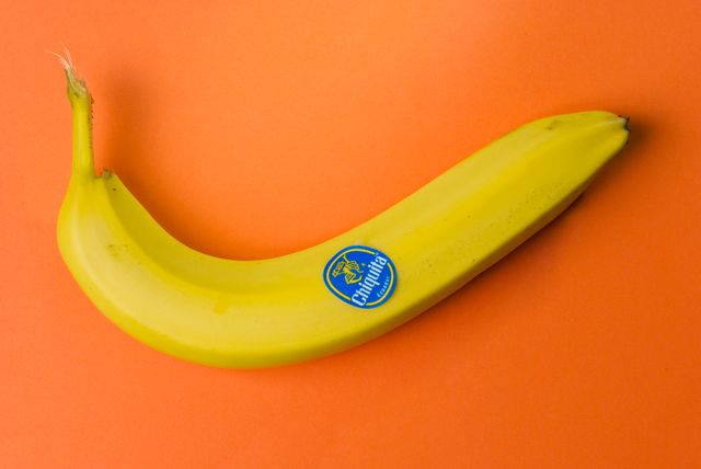Yellow banana rests against vibrant orange backdrop. Its vibrant tones create striking contrast, making it ideal for visual contexts requiring strong color dynamics. Perfect for advertisements, health illustrations, nutrition blogs, bright and contemporary designs, or any project focused on food and healthy eating.