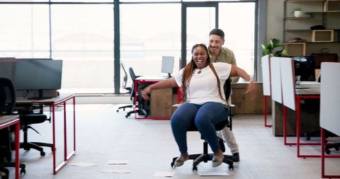 Colleagues engaging in playful office chair ride