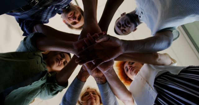 A diverse group of individuals places their hands together in a gesture of unity and teamwork, with copy space. Their collaboration symbolizes solidarity and a shared goal or commitment.
