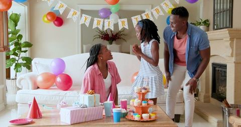 Family Celebrating Daughter's Birthday with Cake and Balloons at Home
