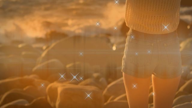 Woman stands on rocks near the sea during sunset with animated sparkling stars adding a romantic and dreamy vibe. Ideal for use in themes related to love, relaxation, and seaside escapes.