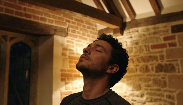 Man reflecting with closed eyes in rustic brick and stone interior, warm contemplative atmosphere
