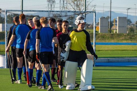 Male Field Hockey Teams Shaking Hands in Front of Goal Net