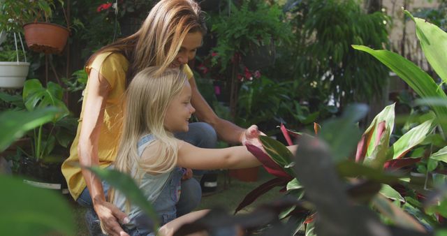Happy caucasian mother and daughter touching plants in sunny garden - Download Free Stock Photos Pikwizard.com